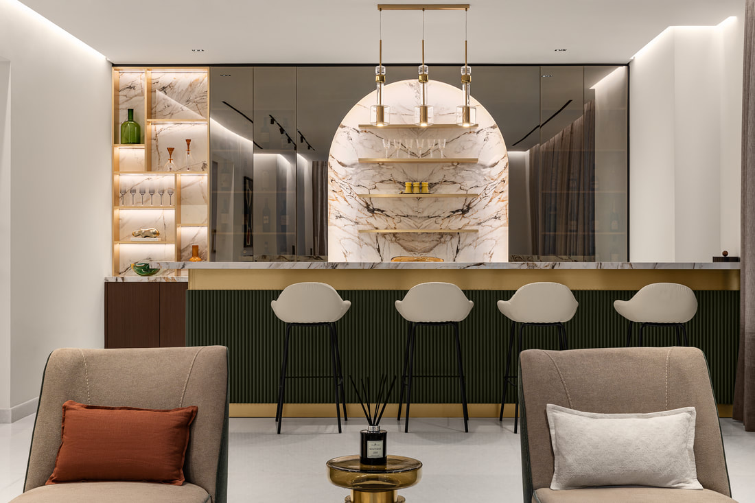 Home bar interior design with marble backdrop, brass shelving and green fluted panelling in a Dubai villa